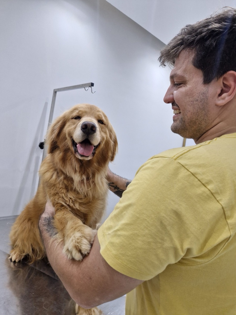 Fernando, da equipe The Vet, abraçado com um golden retriever